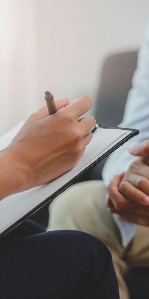 Psychiatrist taking note during consultation with patient.